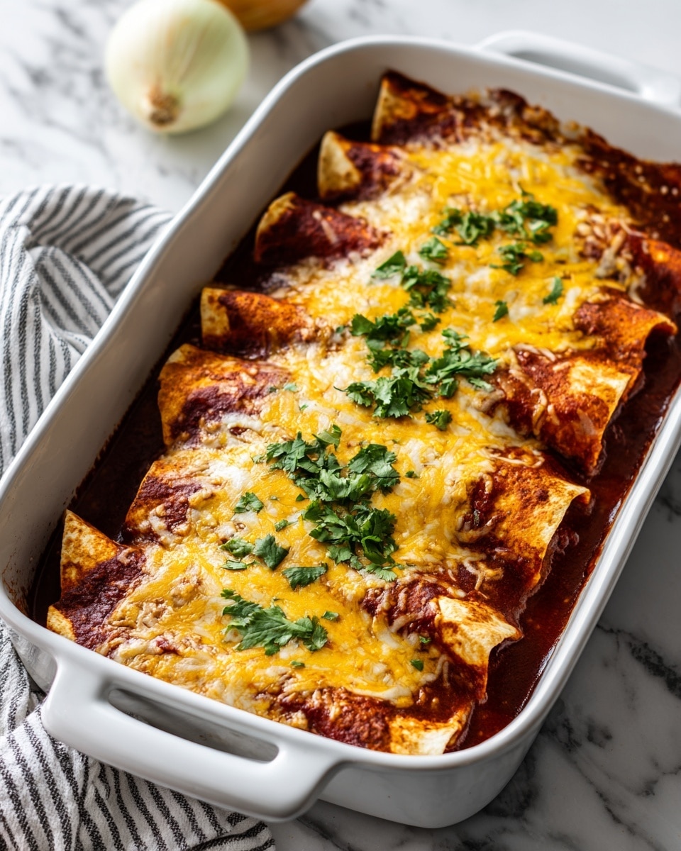 The image shows a white baking dish filled with baked enchiladas. The dish is full of several rolled tortillas layered with a rich red sauce, melted yellow and white cheese on top, and sprinkled with fresh green cilantro. The cheese is melted with some texture and slight browning. The edges show darker crispy spots where the sauce and cheese meet the dish. A sliced onion and a striped cloth are partly visible on a white marbled surface in the background. photo taken with an iphone --ar 4:5 --v 7