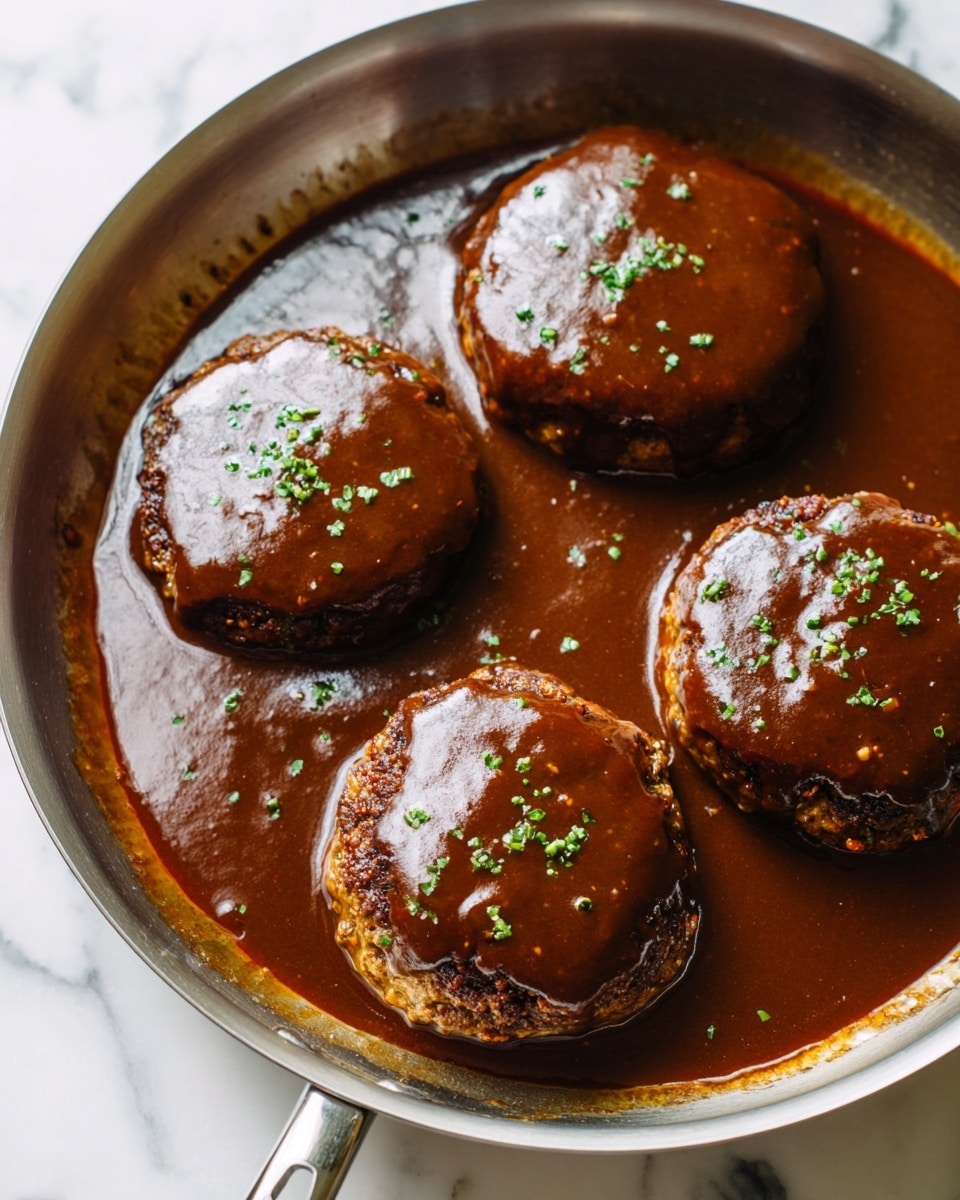 The image shows a close-up of four thick, round patties inside a silver pan, each covered with a smooth dark brown sauce that glistens under the light. The patties have a slightly rough texture, with a few small cracks visible under the sauce. Small green herb bits are sprinkled evenly on top of each patty, adding a touch of color contrast. The sauce spreads thinly around the patties, filling the pan with a shiny, rich layer. The pan sits on a white marbled surface, and the whole scene looks warm and inviting. photo taken with an iphone --ar 4:5 --v 7