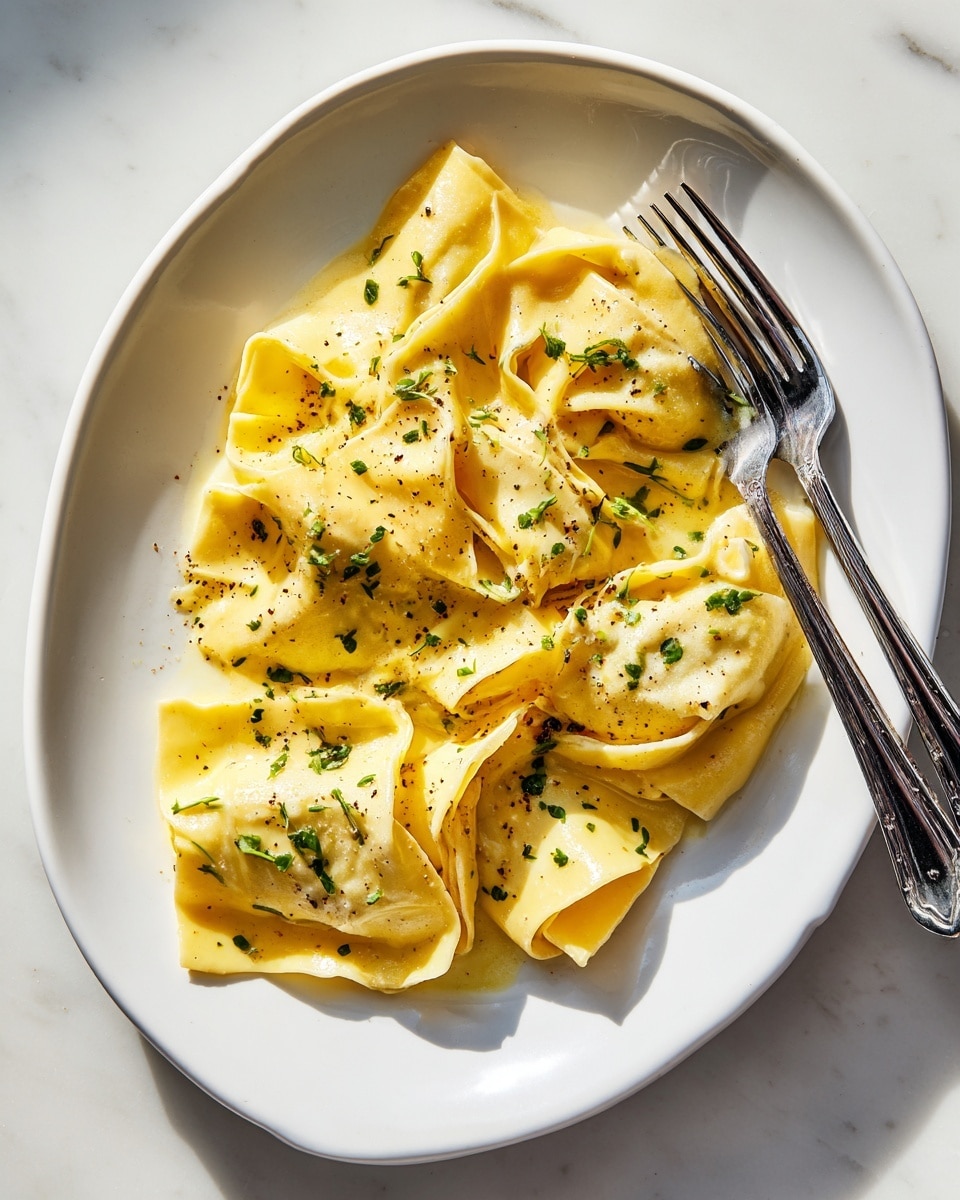 A white oval plate holds a generous piled portion of wide, flat pasta ribbons coated in a creamy, pale yellow sauce with small specks of black pepper and grated yellow zest scattered throughout. The pasta is soft and slightly curled, layered unevenly with some folds visible on top, giving it a textured look. Two silver forks with delicate patterns rest on the right side of the plate, partially embedded among the pasta. The plate sits on a white marbled surface with gentle light and shadow falling across, creating a warm, inviting scene. photo taken with an iphone --ar 4:5 --v 7