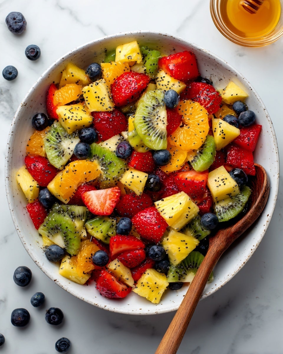 A clear glass bowl filled with a colorful mix of fresh fruit pieces sits on a white marbled surface. The fruit includes bright red strawberry halves with their smooth inner texture and outer seeds visible, orange tangerine slices with a slightly shiny surface, yellow pineapple chunks showing fibrous detail, green kiwi pieces displaying their soft flesh and small black seeds, and small, round dark blueberries scattered throughout. Tiny black seeds are sprinkled evenly over the fruit, adding a speckled contrast to the vivid colors. A silver spoon rests inside the bowl, partially visible among the fruit. The background and surface are clean and white with subtle marbled patterns. photo taken with an iphone --ar 4:5 --v 7