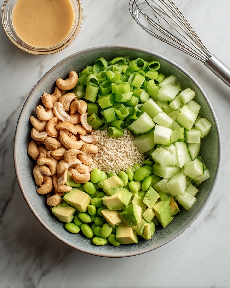 A bowl with six separate layers of fresh ingredients arranged neatly: on the top left, a bright green mix of sliced spring onions; next to it on the right, light green cucumber cubes with a smooth texture; below the cucumbers, small white sesame seeds scattered lightly; to the left of the sesame, light brown cashew nuts with a crunchy look; below the cashews, bright green edamame beans with a shiny surface; and on the bottom left, soft avocado cubes in a pale green shade. The bowl is placed on a white marbled surface, with a glass bowl of light tan sauce and a whisk visible on the upper right side. Photo taken with an iphone --ar 4:5 --v 7