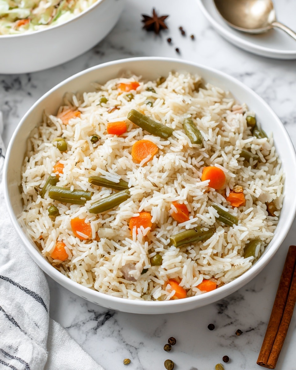A white bowl filled with cooked rice mixed with small pieces of orange carrots, green beans, and small bits of white meat scattered throughout. The rice grains are fluffy and separated, showing a soft texture. The bowl is placed on a white marbled surface with a few whole peppercorns and a cinnamon stick nearby. In the background, there are hints of another white bowl with a creamy salad and a white cloth with black stripes on the side. Photo taken with an iphone --ar 4:5 --v 7