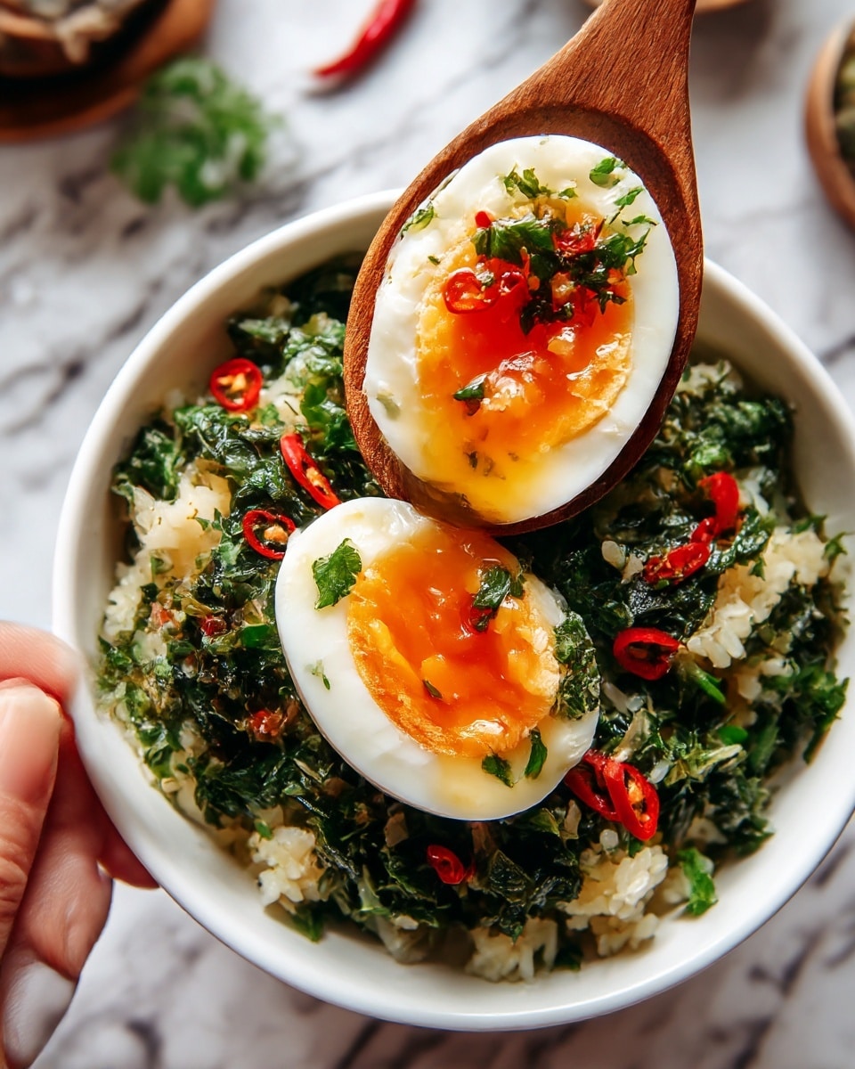 A white bowl filled with rice mixed with chopped green herbs and sliced red chili peppers, topped with a halved soft-boiled egg with a white outer layer and bright orange yolk center. A wooden spoon with a woman's hand holding it lifts one half of the egg above the bowl, showing the glossy yolk inside. The background has a white marbled texture with blurred kitchen items. Photo taken with an iphone --ar 4:5 --v 7