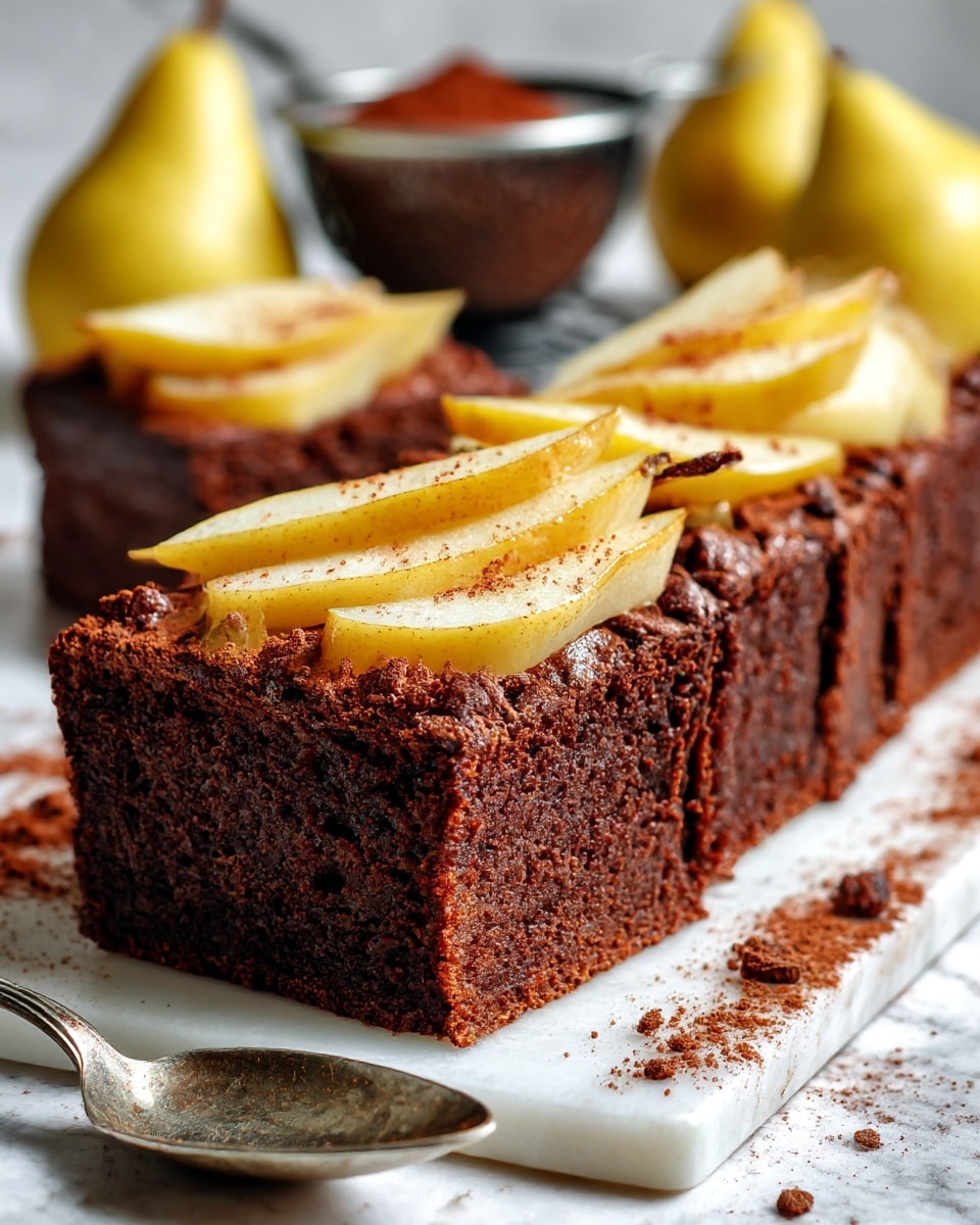 Three triangular slices of dark brown chocolate cake with light yellow pear slices baked on top are placed on a white square plate. The cake layers look thick and moist, with an uneven, crumbly texture around the edges. The pear slices are soft and slightly glossy, sitting close to the surface of the cake. The plate rests on a white marbled surface, and a tarnished silver spoon lies beside it. In the background, there are whole yellow pears and a small round metal sieve with cocoa powder, slightly blurred. Photo taken with an iphone --ar 4:5 --v 7