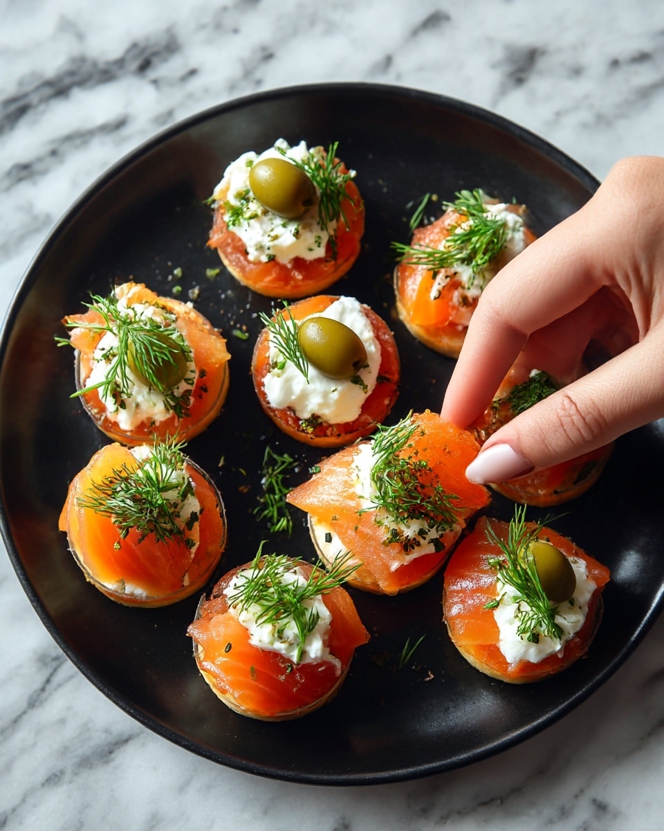 A black plate holds six small appetizers. Each appetizer has three clear layers: the bottom layer is thin slices of orange smoked salmon wrapped in a round shape, the middle layer is a white creamy dollop placed right in the center, and the top layer has a green olive sliced horizontally placed on the cream with small sprigs of fresh green dill arranged around the olive. A woman's hand is picking up one of the appetizers from the plate. The plate sits on a white marbled surface. photo taken with an iphone --ar 4:5 --v 7